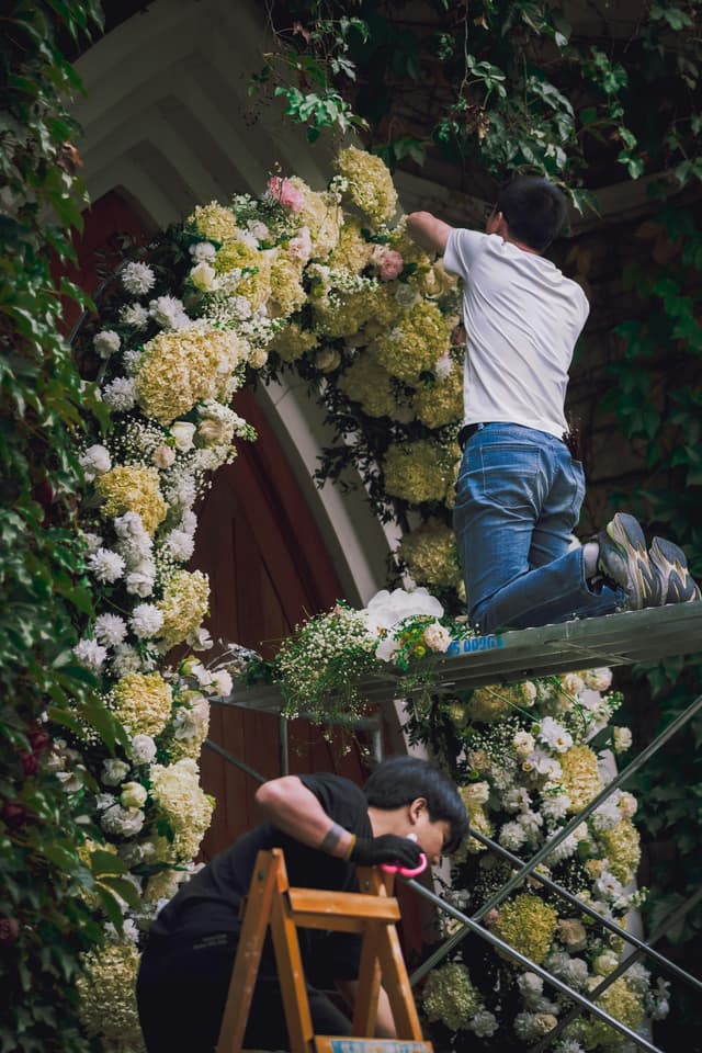 Two florists installing a large floral arch